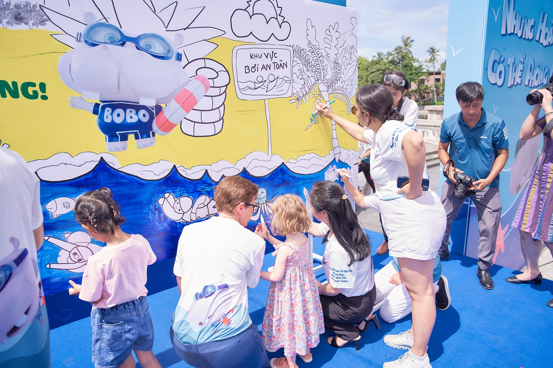 Tiến sĩ Angela Pratt, Trưởng đại diện Tổ chức Y tế Thế giới tại Việt Nam cùng các em nhỏ thực hiện bức tranh khổng lồ về phòng chống đuối nước
